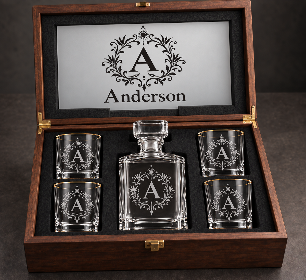 Anderson monogram gift set rendering with empty gold-rim glasses and decanter, acrylic inner lid recessed into black foam